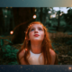 Child smiling in awe while looking at glowing lights in the forest